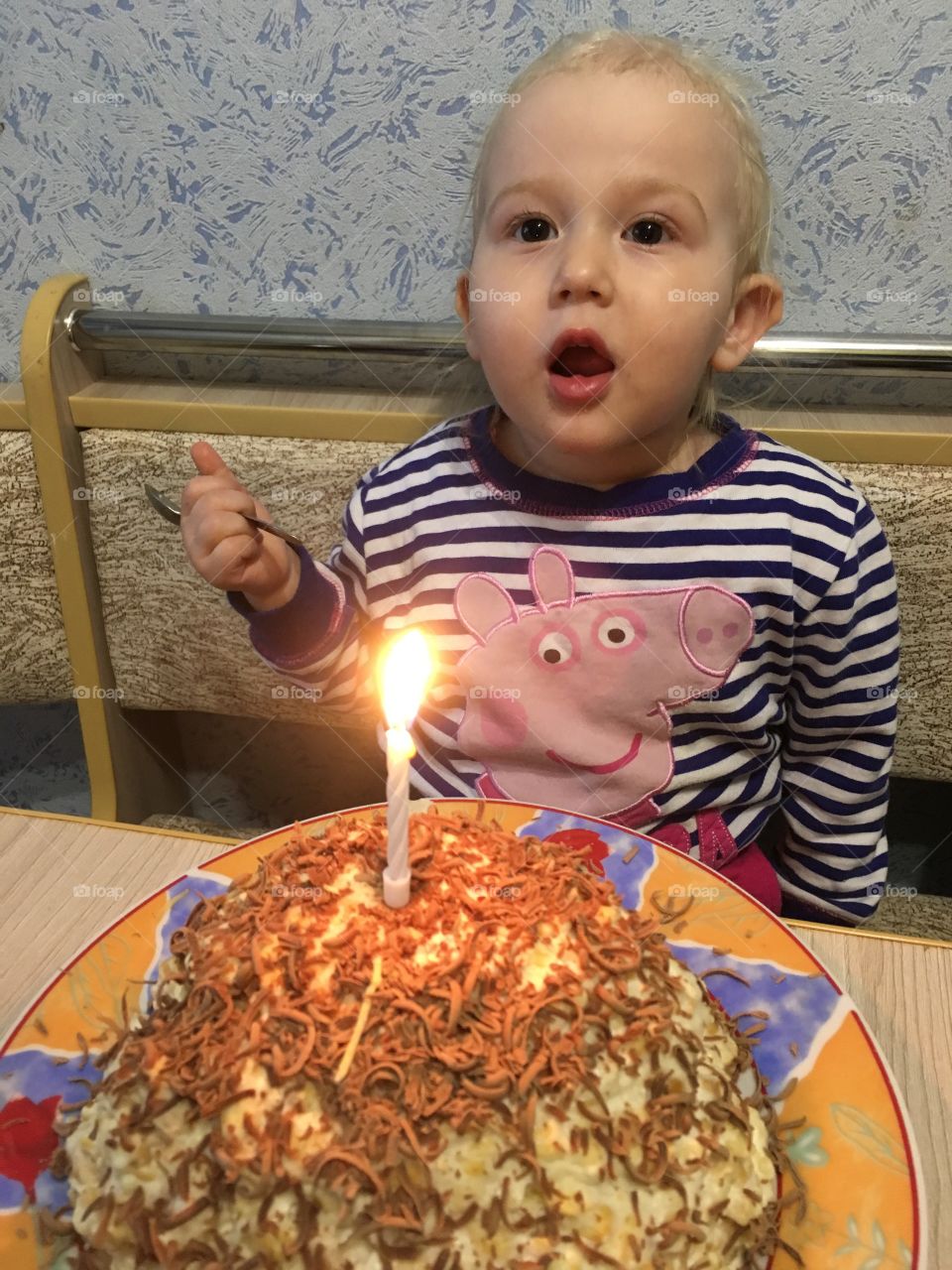 Ребёнок задувает свечу на торте