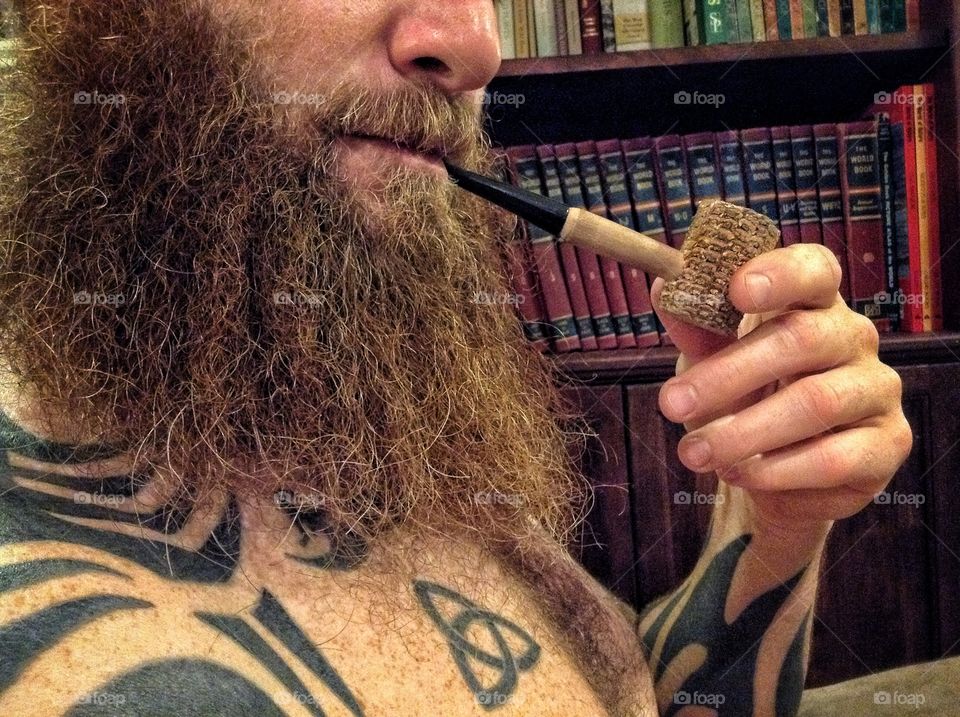 A bearded man smoking a Corn Cob pipe.