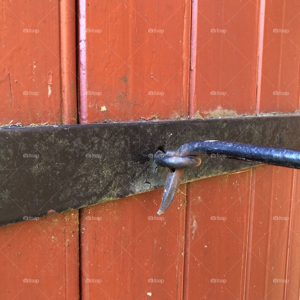 Old iron hook on red wooden door close up