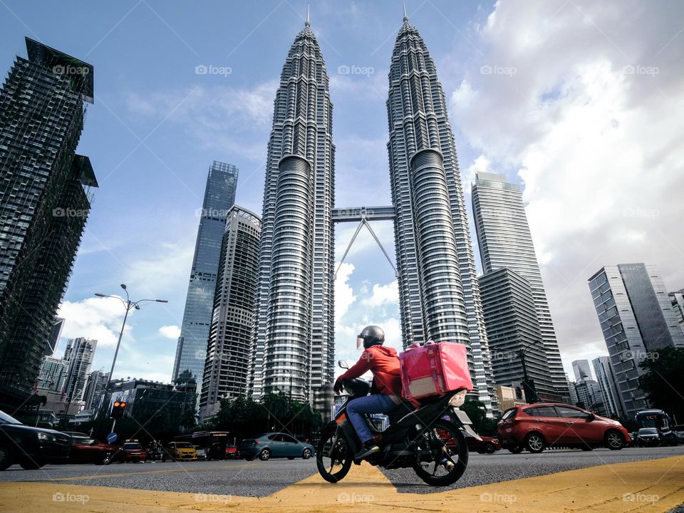 Delivery rider in front of the Petronas Twin Towers, Kuala Lumpur