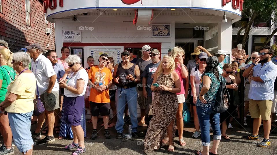 Crowd of people waiting on sidewalk, waiting crowd. Parade is coming. Adults waiting in summer on roadside. Group of people.