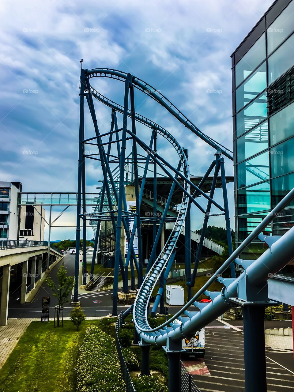 A twisted roller coaster between buildings against a very blue sky.