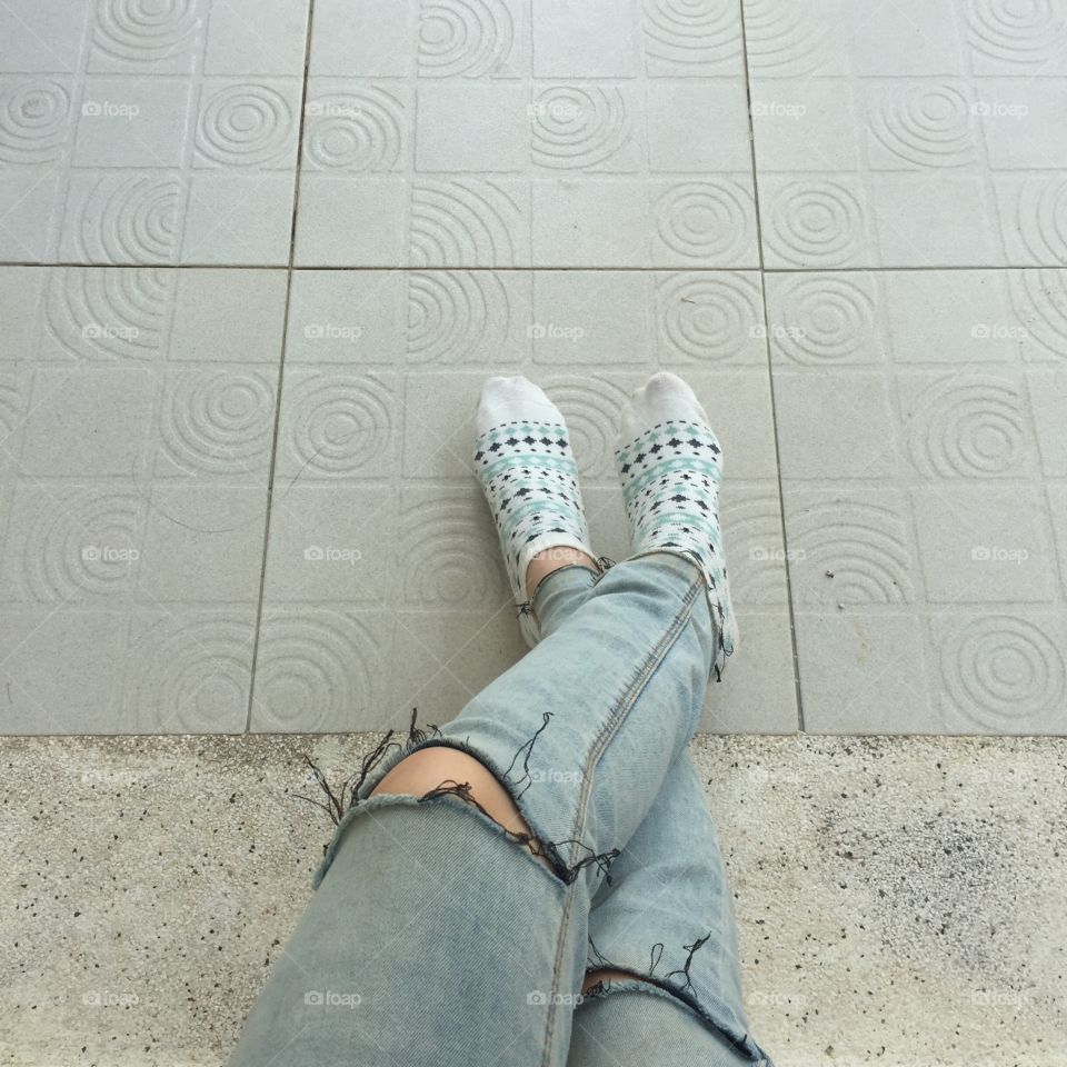 Selfie feet wearing white vintage socks on floor background, jeans and feet great for any use.
