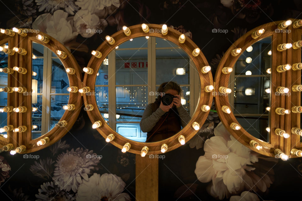 Reflection of a woman photographing in mirror