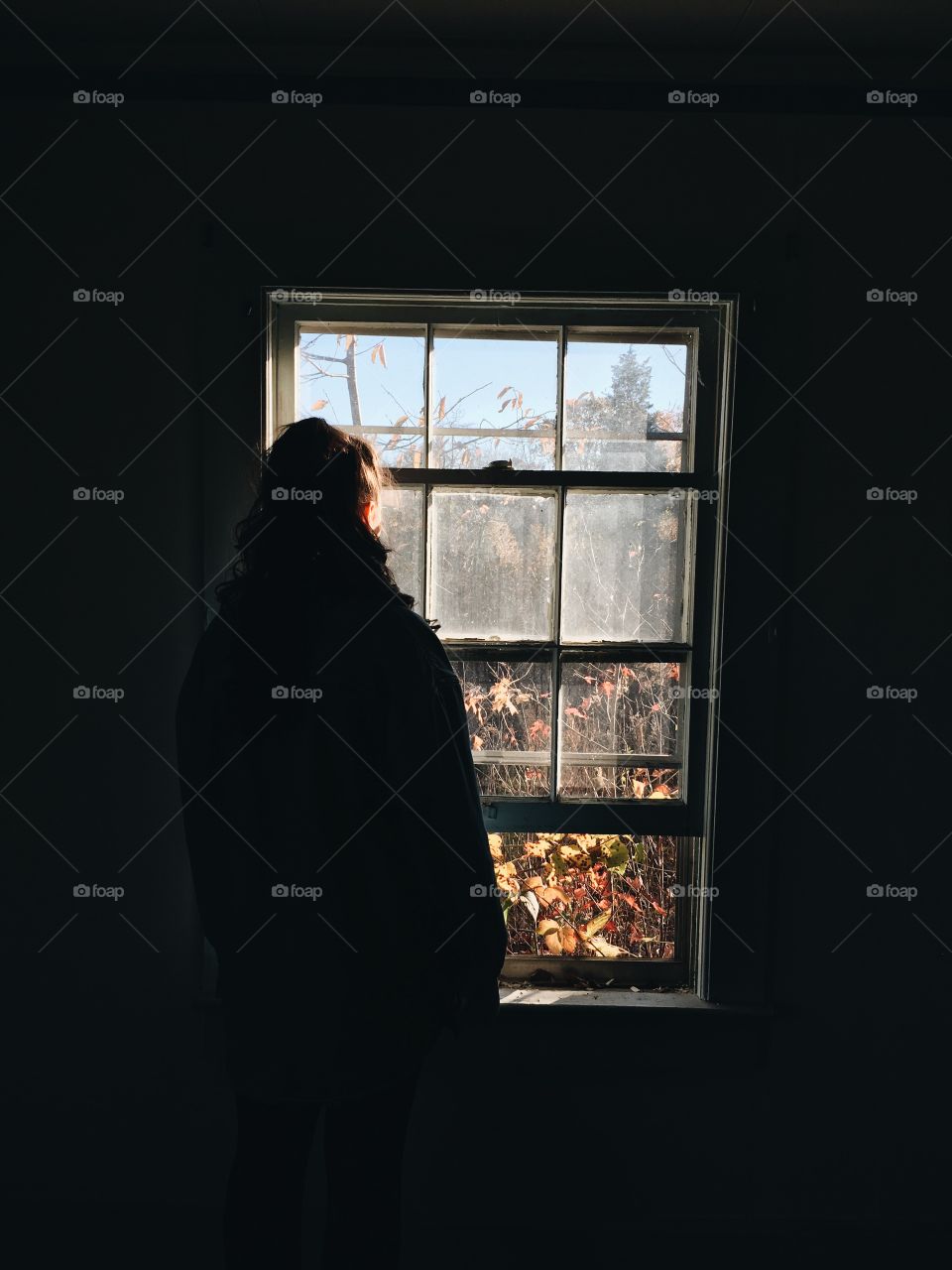 Rear view of a woman looking through window