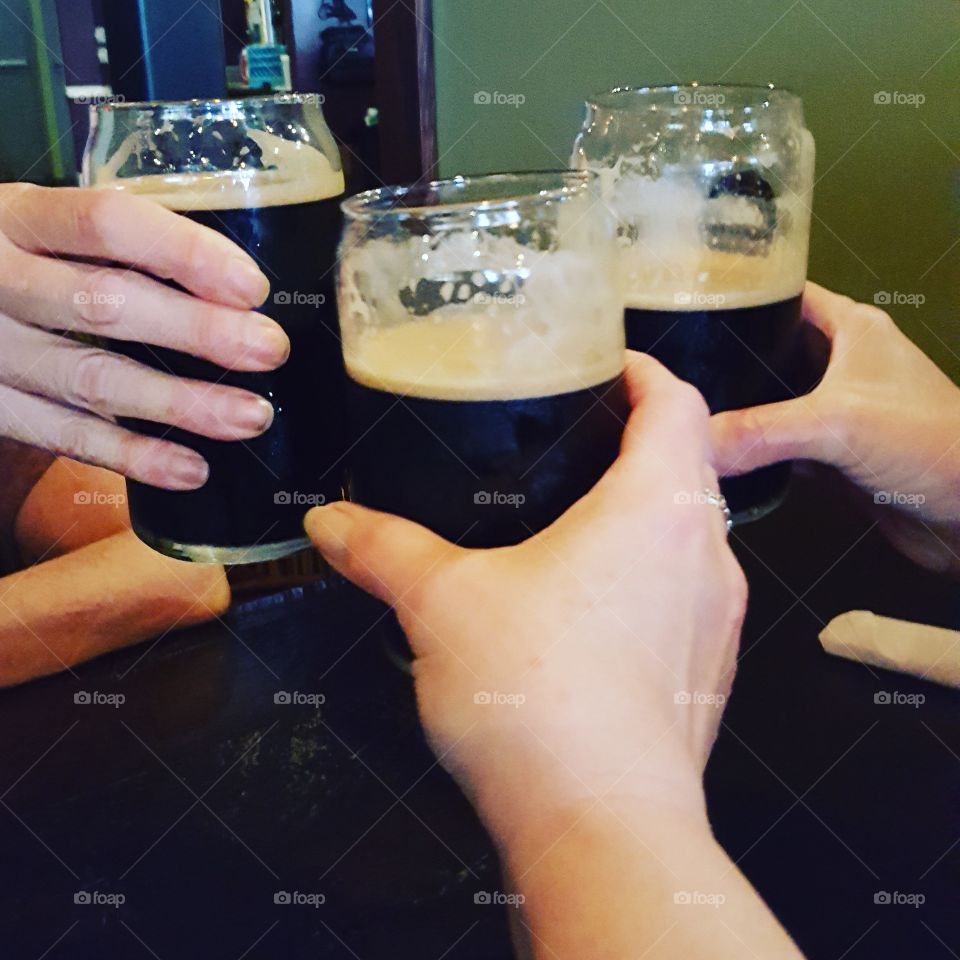 Cheers! Celebratory toast with dark beer starts off a fun night with friends.