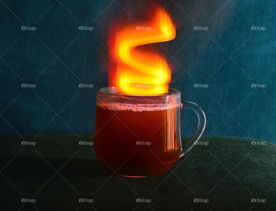 transparent glass filled with hot coffee. Instead of smoke, a curved beam of light comes out of the glass, thanks to the shutter speed.