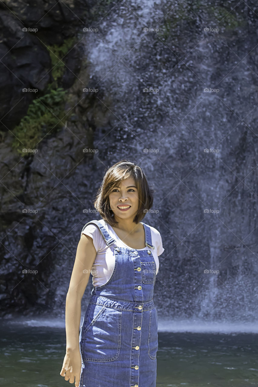 Portrait Asian woman standing in the water and enjoy the Chok Kra-Din WaterFalls at Kanchanaburi in Thailand