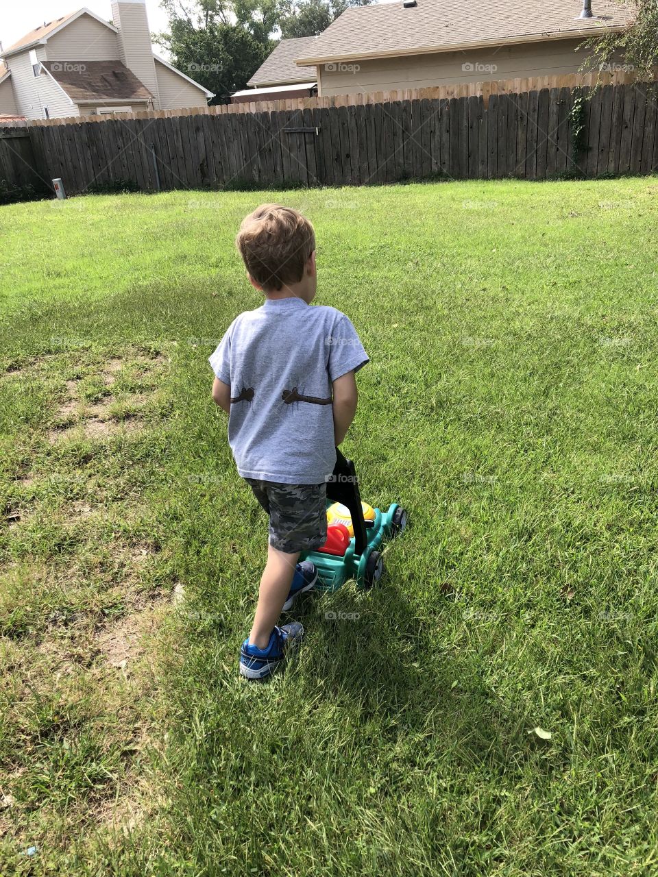 Little boy plays mowing with toy mower