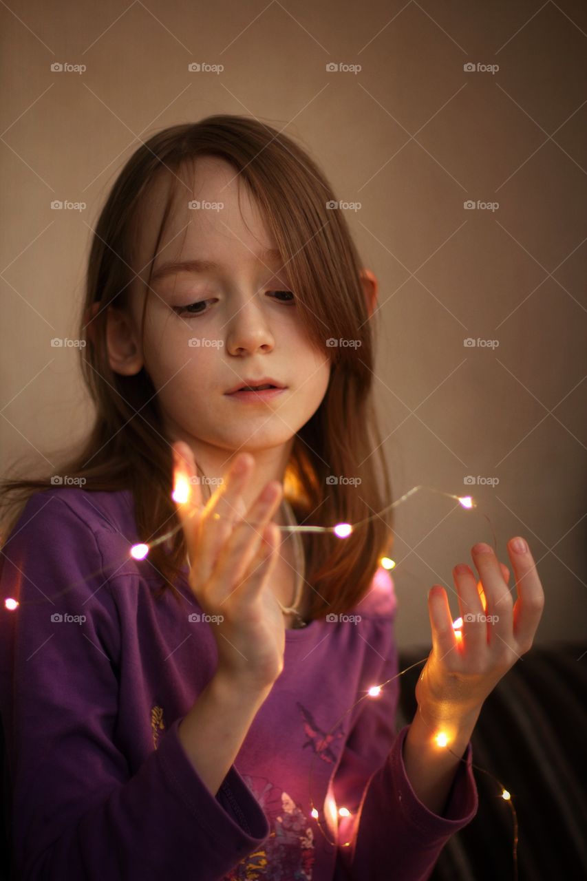The girl looks at the LED garland in her hands