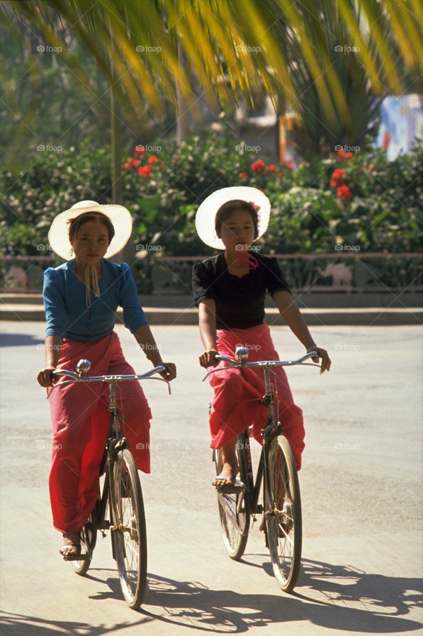 Dai Girl Cyclists in Xishuangbanna, China. This area in the deep south of Yunan province, bordering Burma and Laos, is inhabited by a dozen of the minority tribes; namely the Dai, Han, Hanni, Bulang, Lagu, Wa, Yao, Jinuo, Zhuang, Yi, Hui, and Miao.