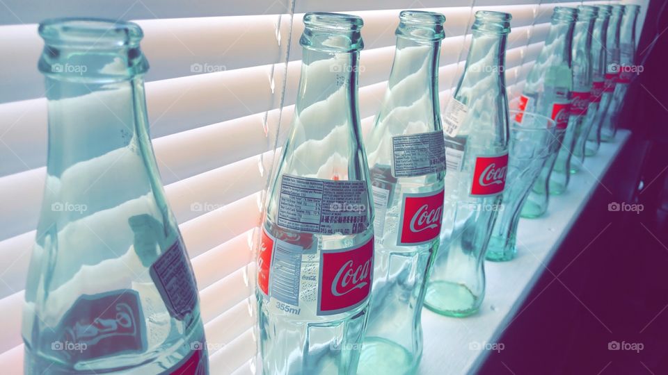 Vibrant clear Coke bottles in a window sill 