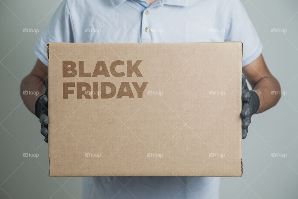 Cardboard box with black friday order written on the box placed on the floor in an empty room with a neutral background. delivery concept. economy concept. black friday concept. shopping concept.