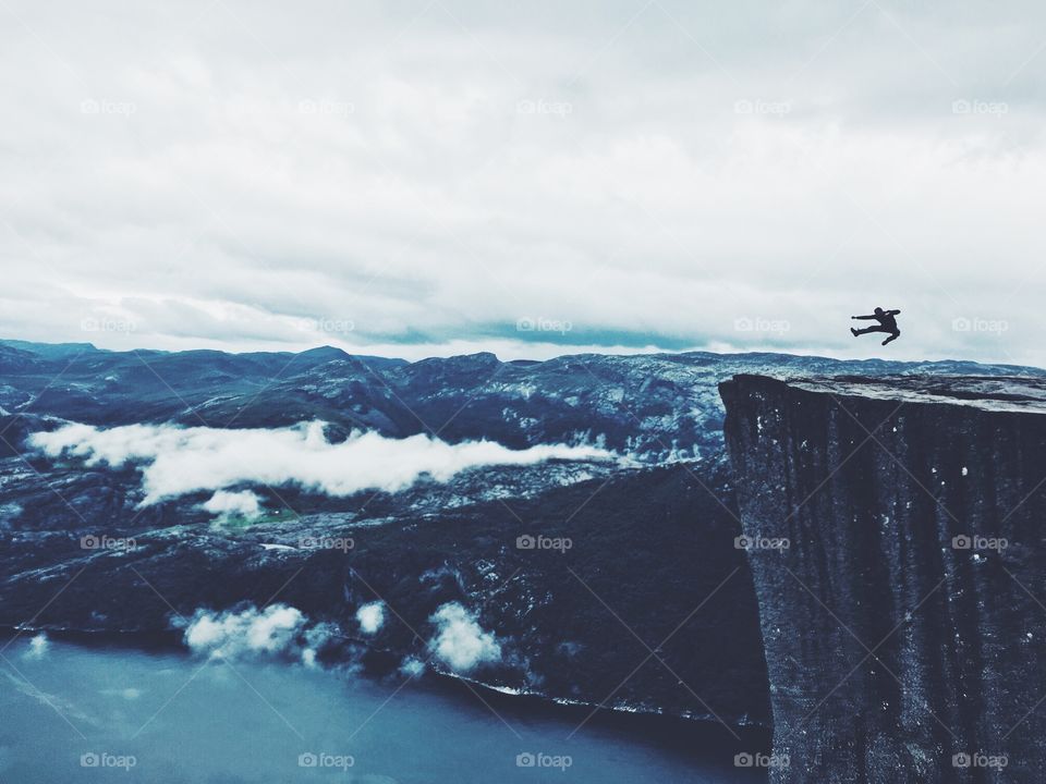 Jumping silhouette on the edge of Prekestolen rock in Norway