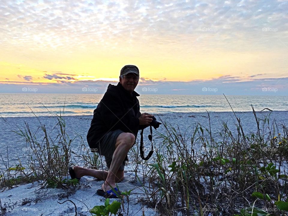 Photographer in silhouette with a lovely yellow sunset and beach dunes.