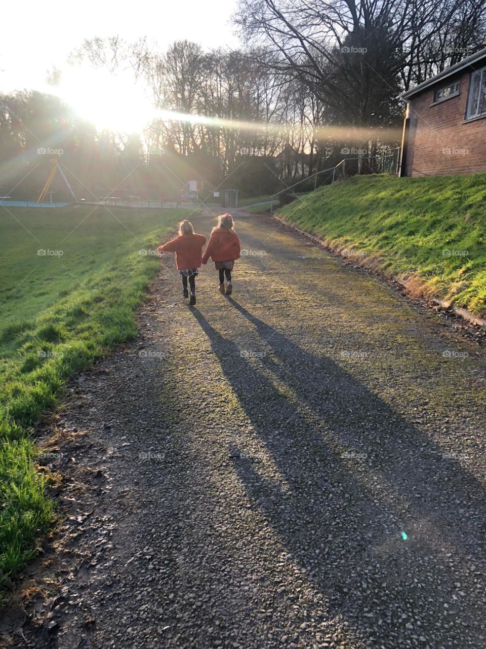 Two little girls holding hands at the park on a sunny winter’s day 