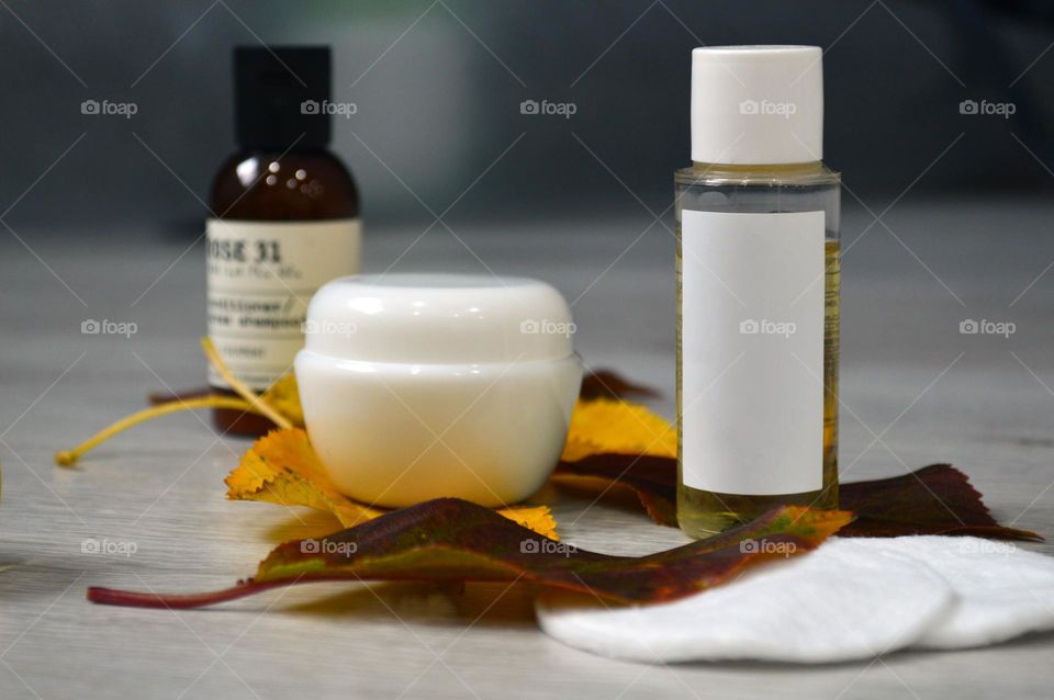 Jars with cream, shampoo and cosmetics on a background with autumn leaves
