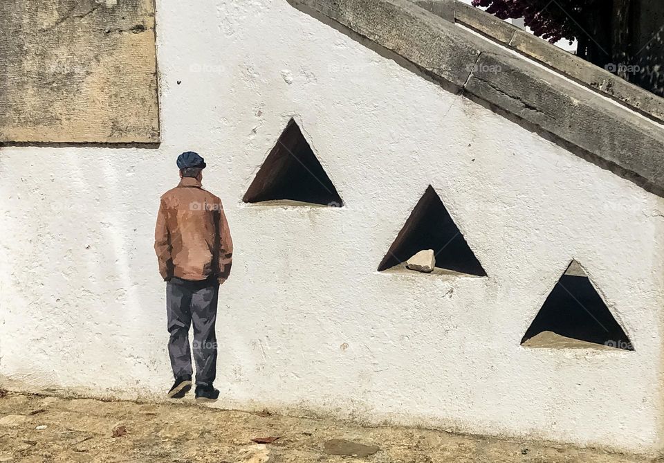 A tiny painted fellows walks by small triangles cut out of a concrete wall