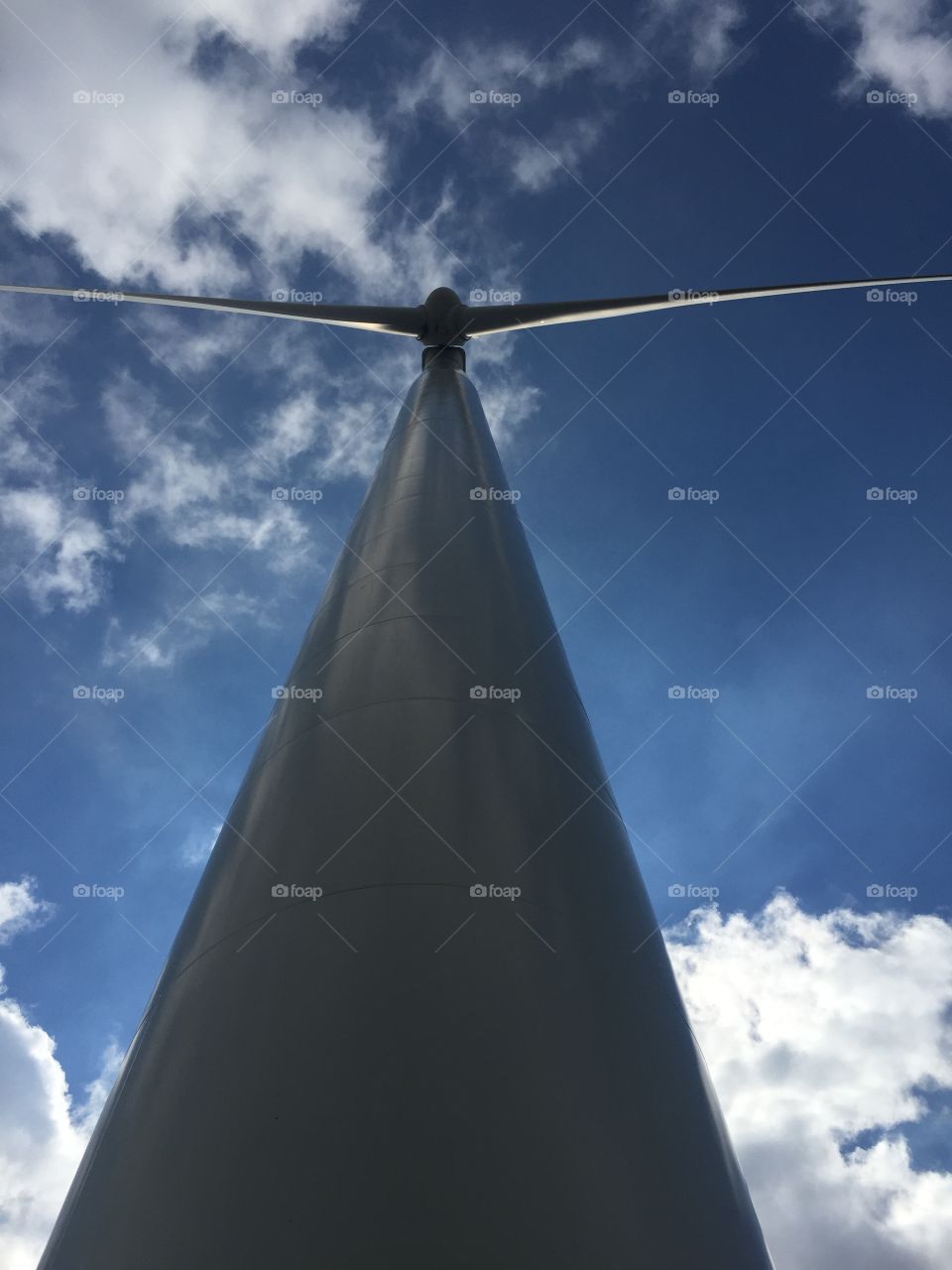 Sunny day clean energy. Standing under a wind generator.