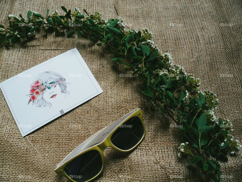 Sunglasses, a sprig of flowers and a postcard