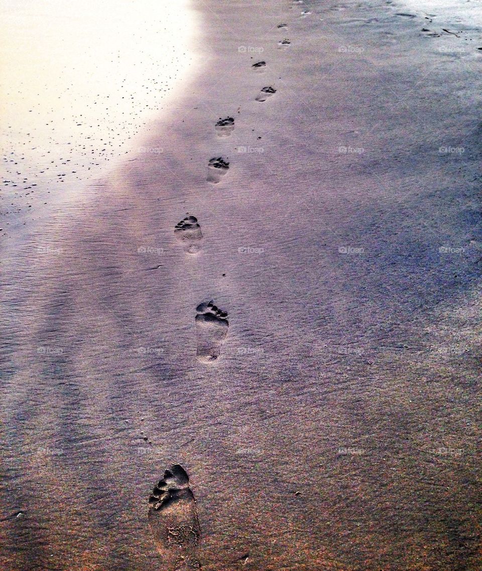 Footprints in the sand at sunset