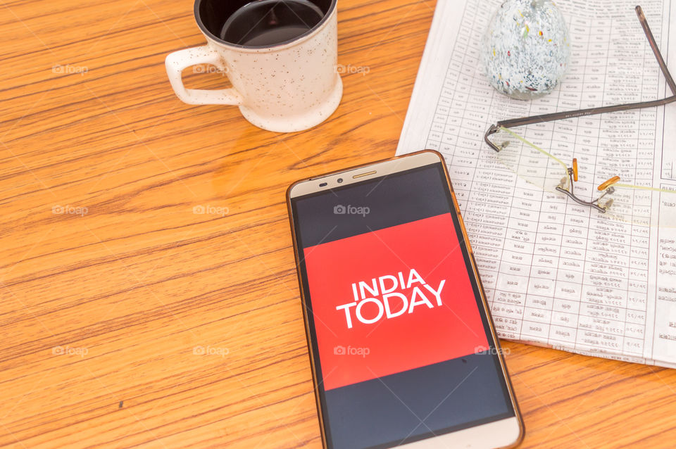 Kolkata, India, February 3, 2019: India Today NEWS app (application) visible on mobile phone screen beautifully placed over a wooden table with newspaper and cup of coffee. A Technology Product Shoot