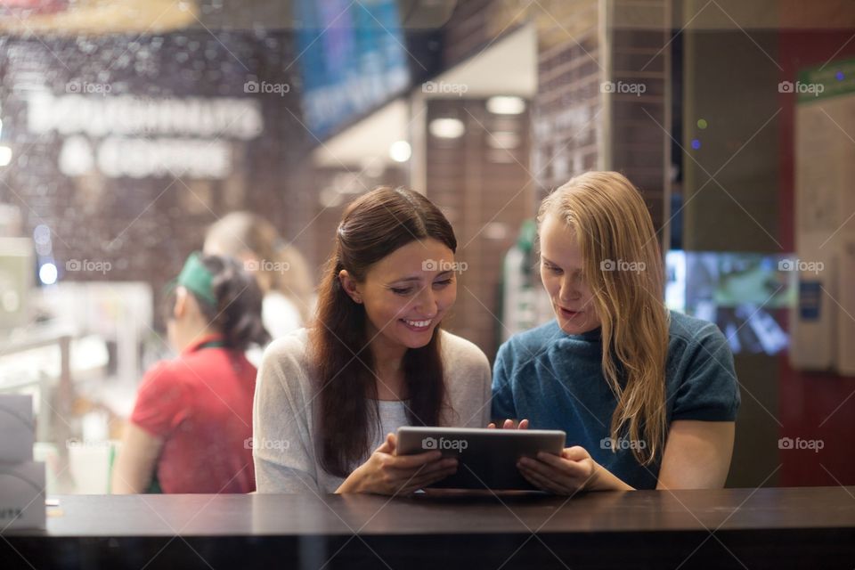 Friends . two friends sitting in a cafe with tablet