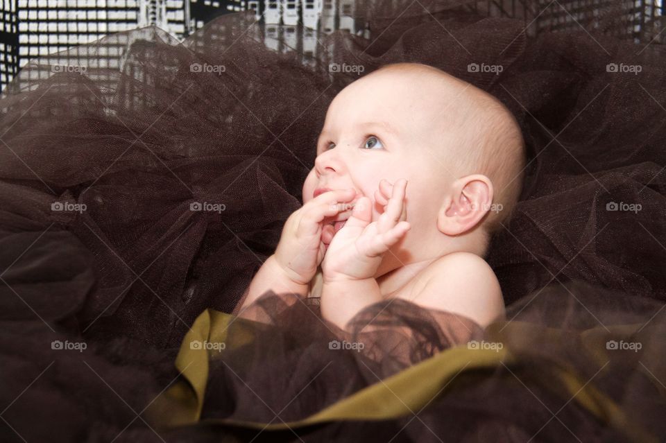 Baby boy sitting on net and licking thumb