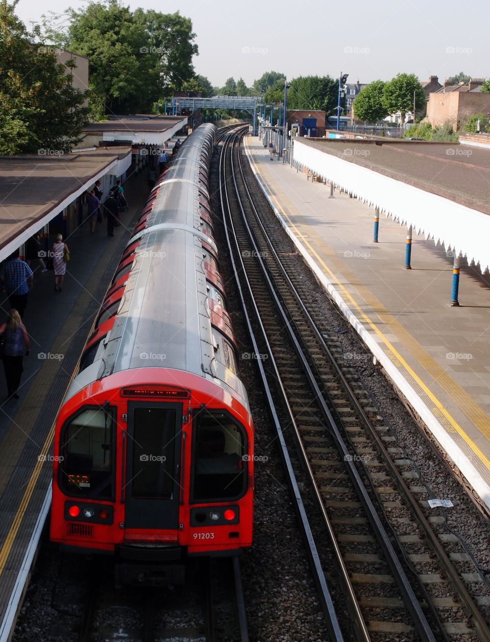 A train pulling into an English station in the summer. 
