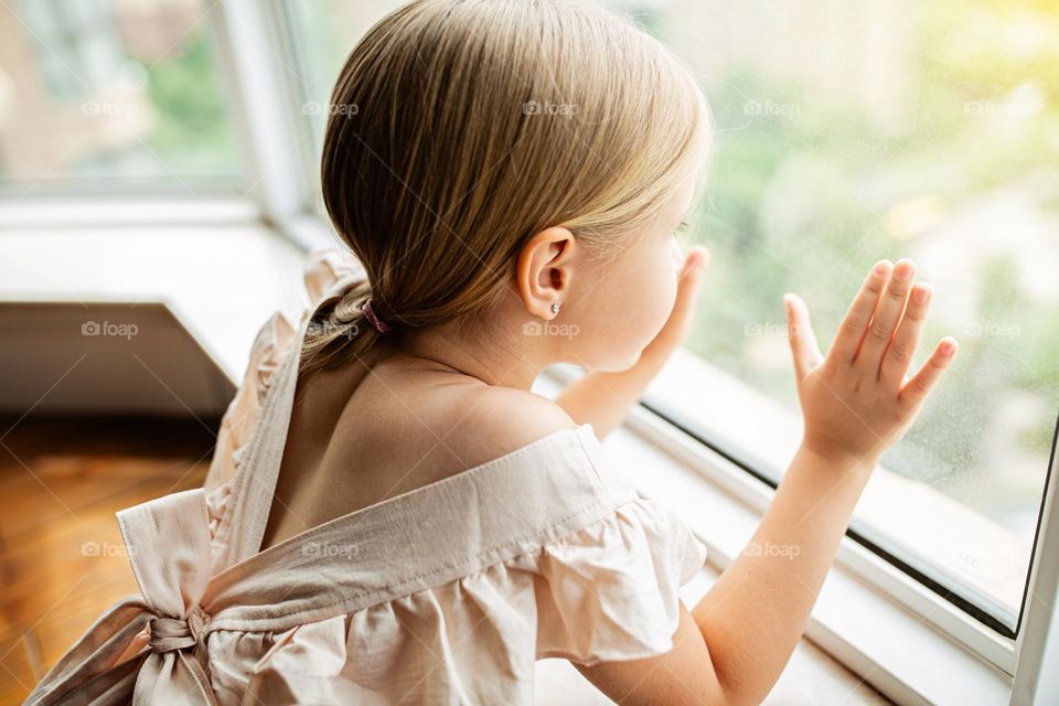 Little girl looking through the window 