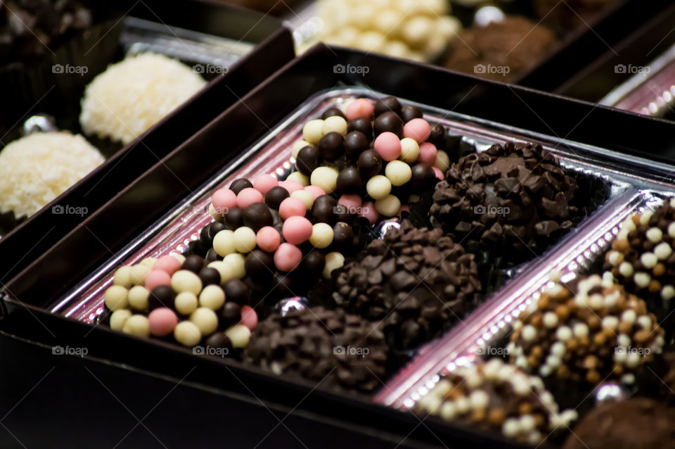 Box of gourmet chocolate truffles decadent cocoa confections decorated with pink and white chocolate balls and curls luxury dessert photography 