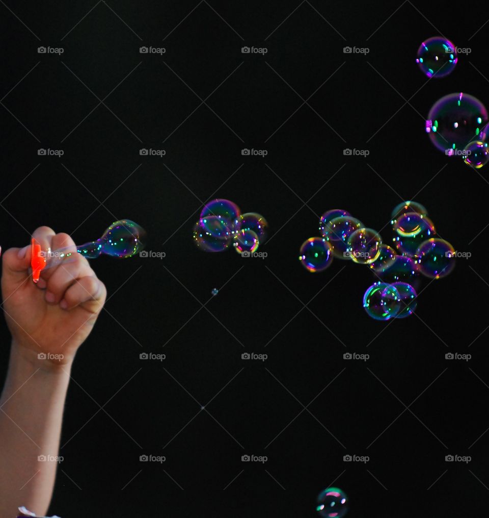Woman hand blowing bubble on black background