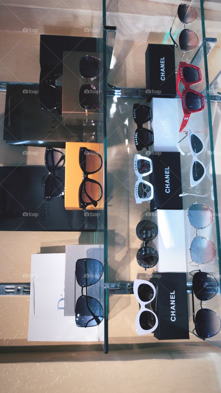 Sunglasses shining on a shelf of a shop . different types ,shapes, colors with the box 