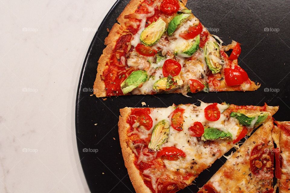 Homemade pizza on a black pizza stone.