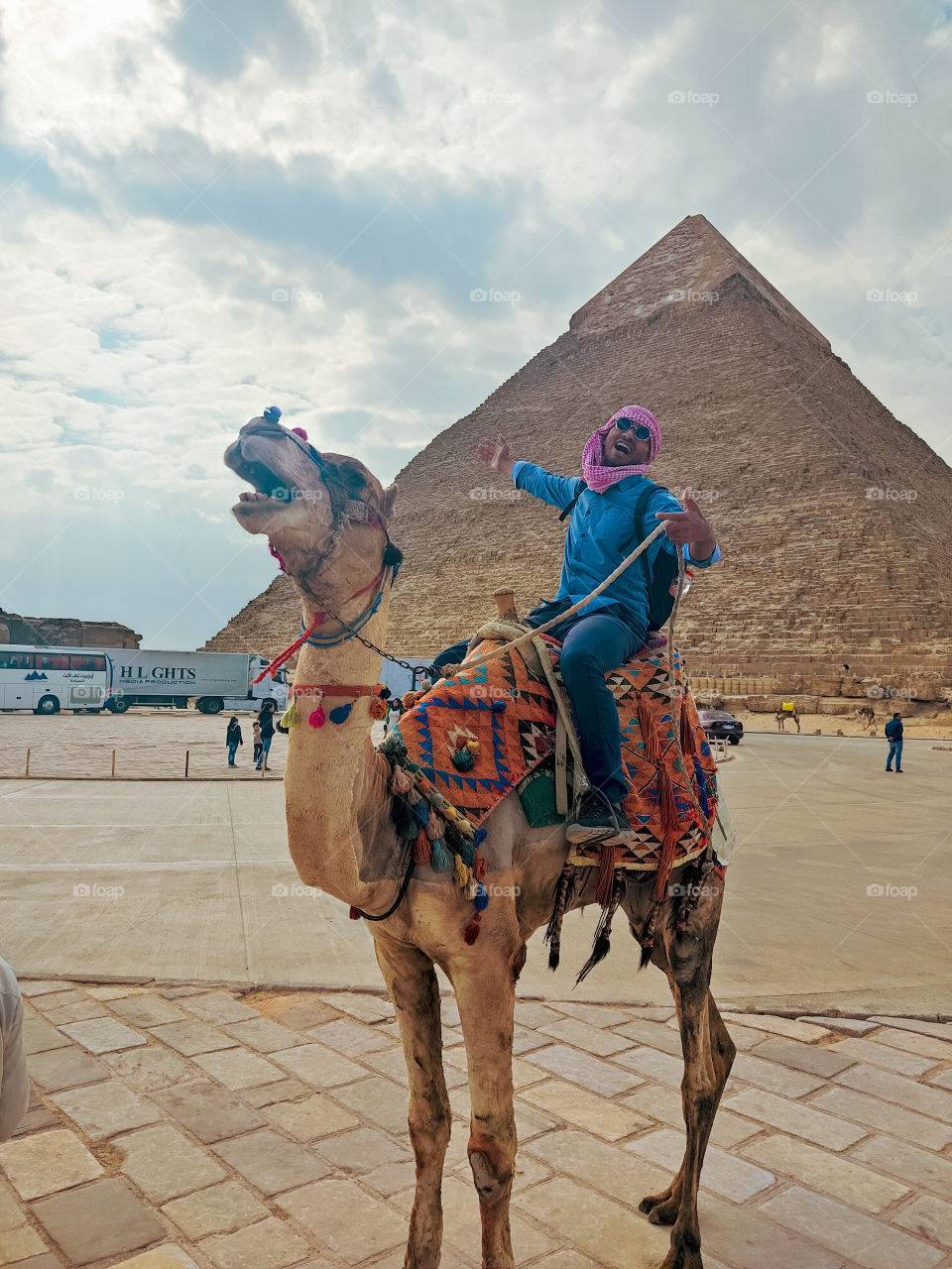 Egyptian young man riding 🐪 camel front of greatest Giza Pyramids at cloudy morning