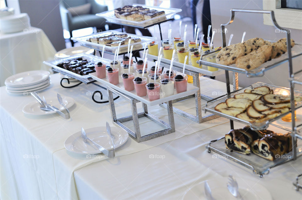 Buffet style dessert table with plates and utensils 