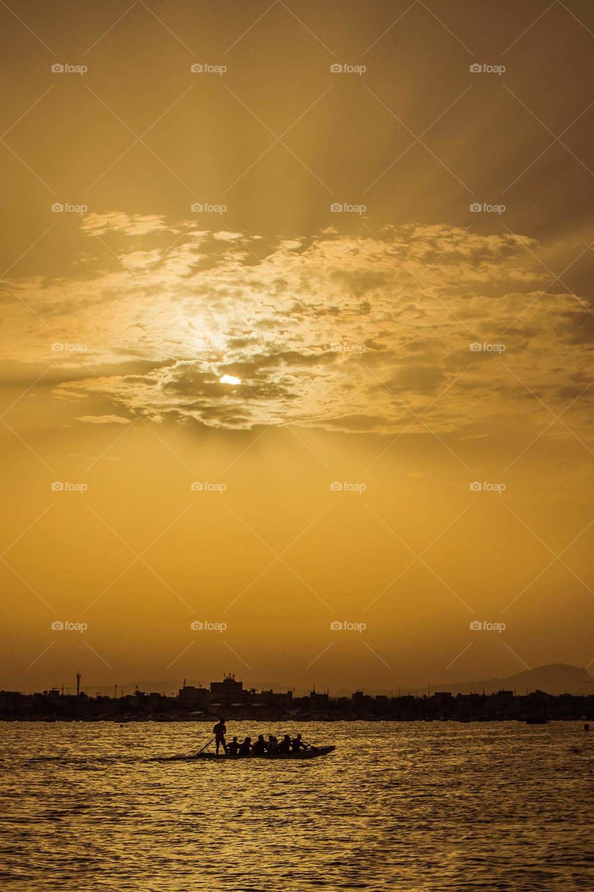 people boat sun sea water river sky sunset