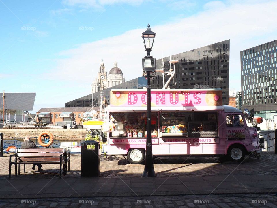 Donut food truck next to the seaside in Liverpool, England with pink bright colours and blue sky.