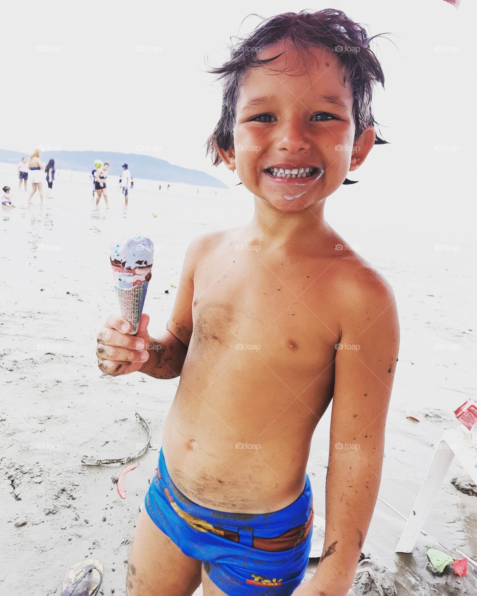 smiling child eating ice cream on the beach