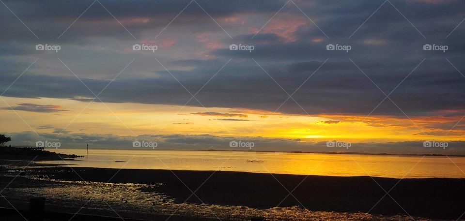 reflections of the sunset at the beach pier in background