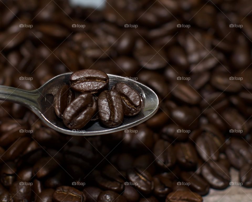 Dark Coffee beans on a teaspoon