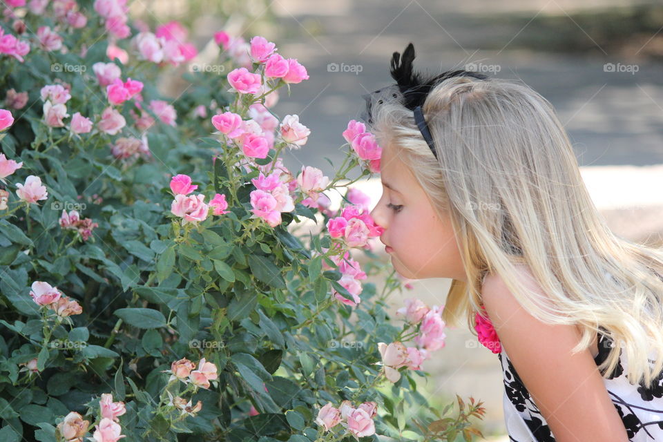 Stop and smell the roses. Girl smelling flowers