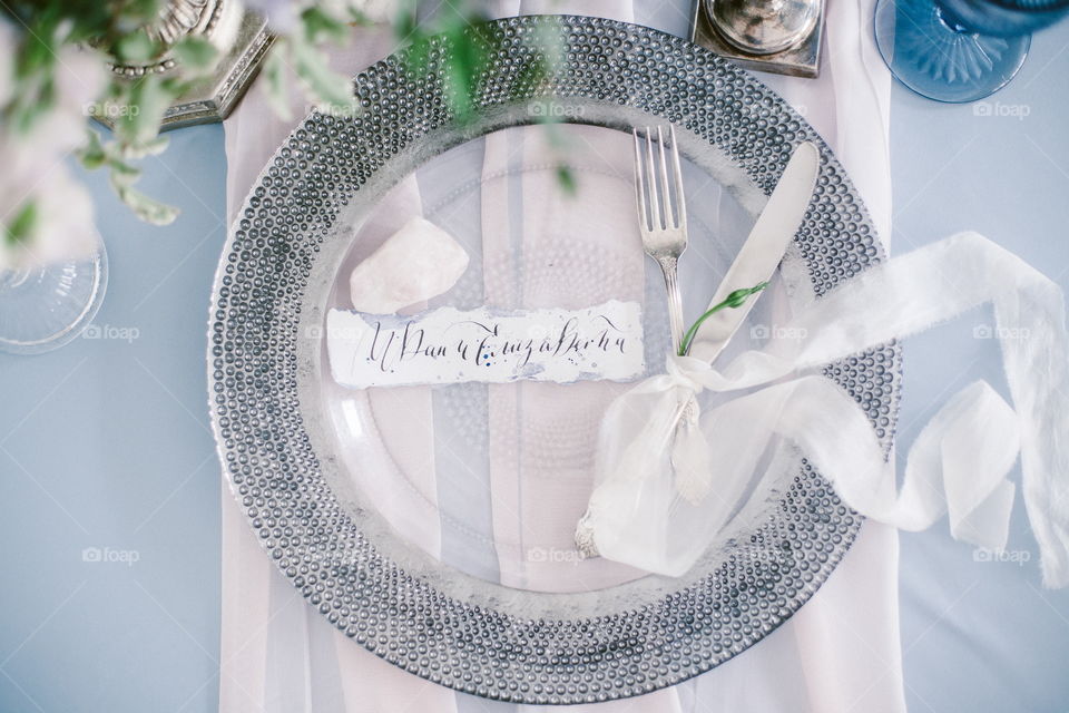 Graphic arts of beautiful wedding calligraphy cards and silver plate with cutlery on festive wedding table. 
