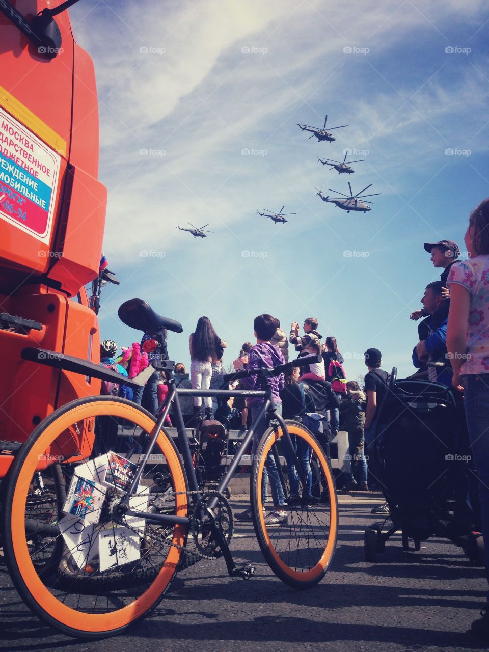 Grey brakeless fixie bike with orange wheels standing on war helicopter parade