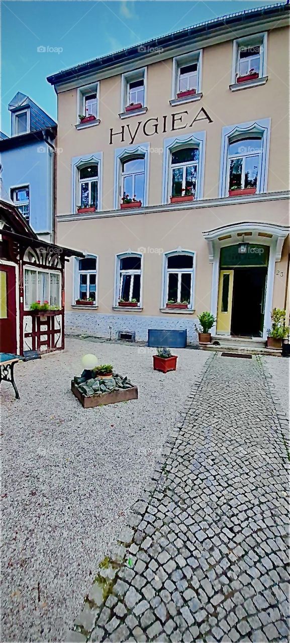 This traditional building is a guest house that will accommodate my sister for her next few days. Lovely accents such as the peach parfait rosé colored facade make one feel right at home here. 2022. Hypnotic Productions