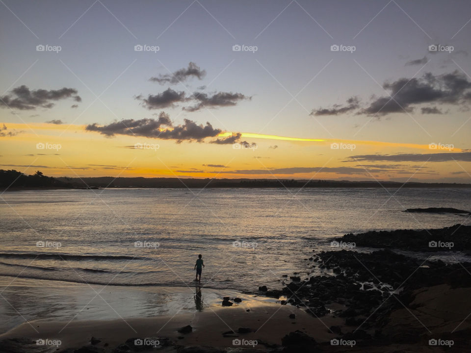 Little boy watching the sunset on the beach