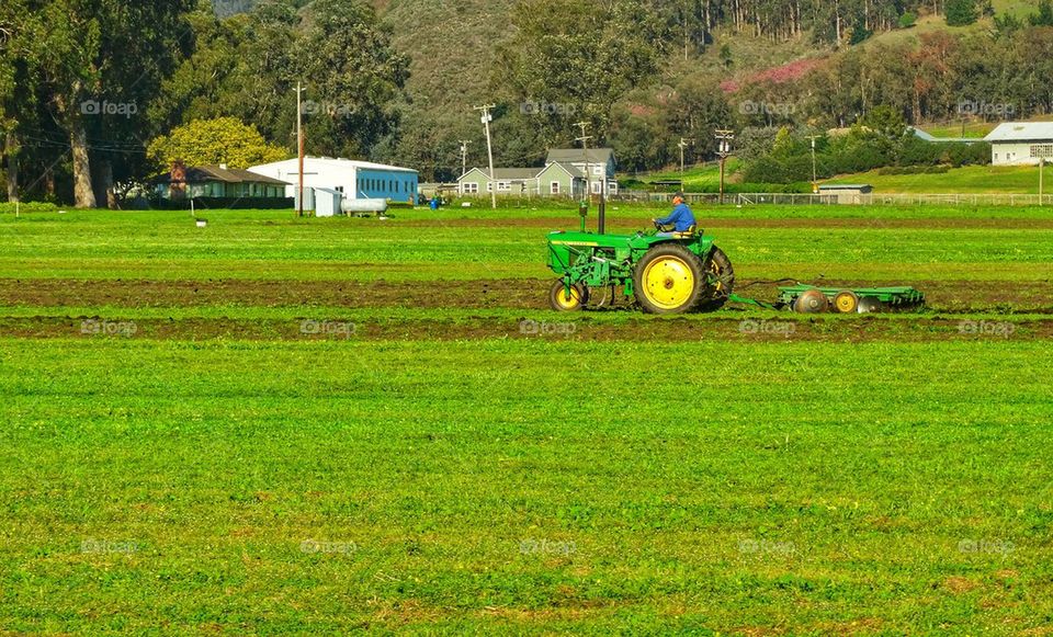 John Deere tractor ploughing field on American farm