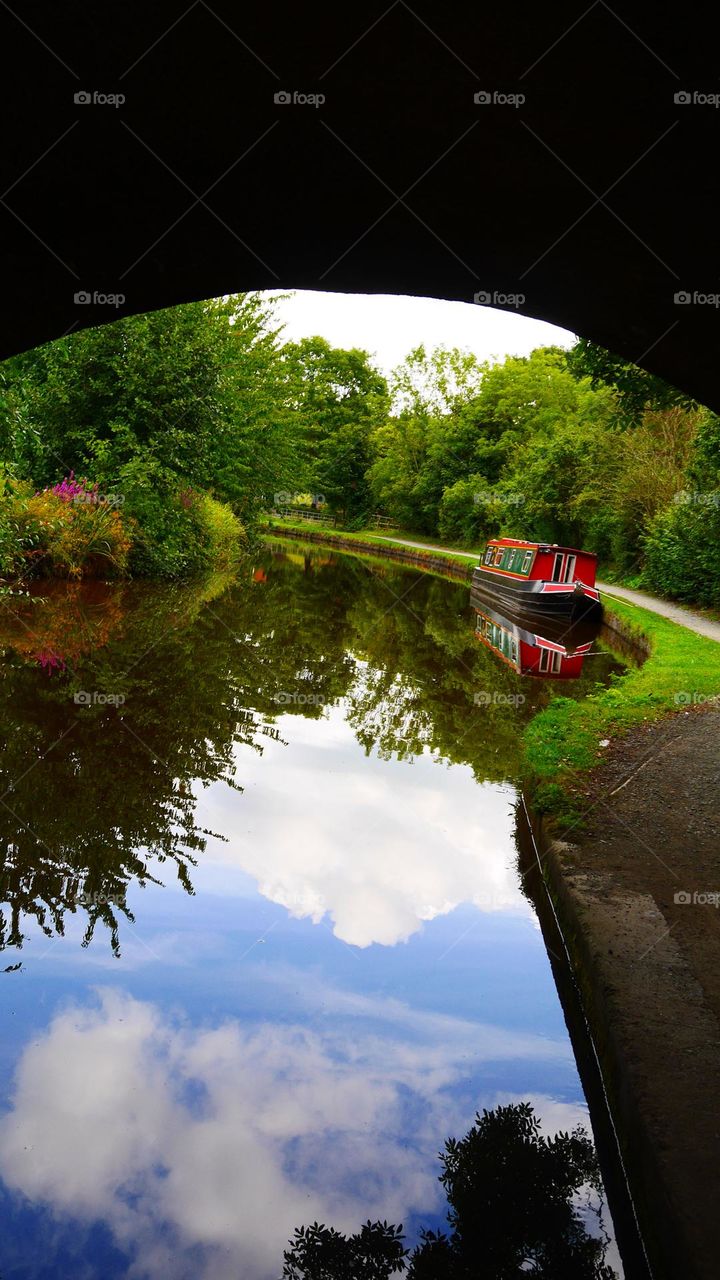 Reflection of slow boat and sky on canal