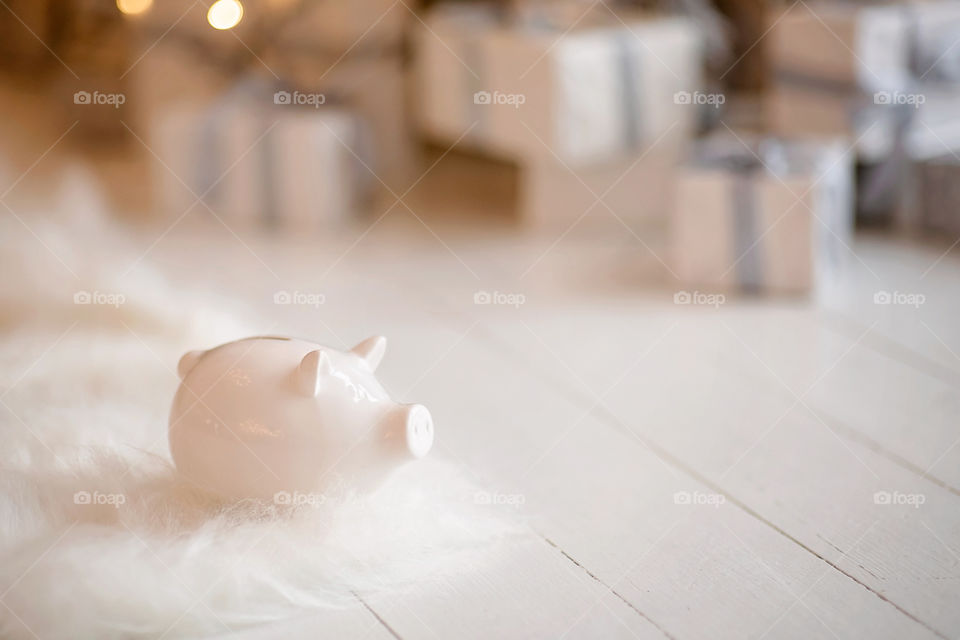 piggy bank with 100 dollars banknote in festive New Year atmosphere of scenery.  Magical bokeh with Christmas tree and bright lights.