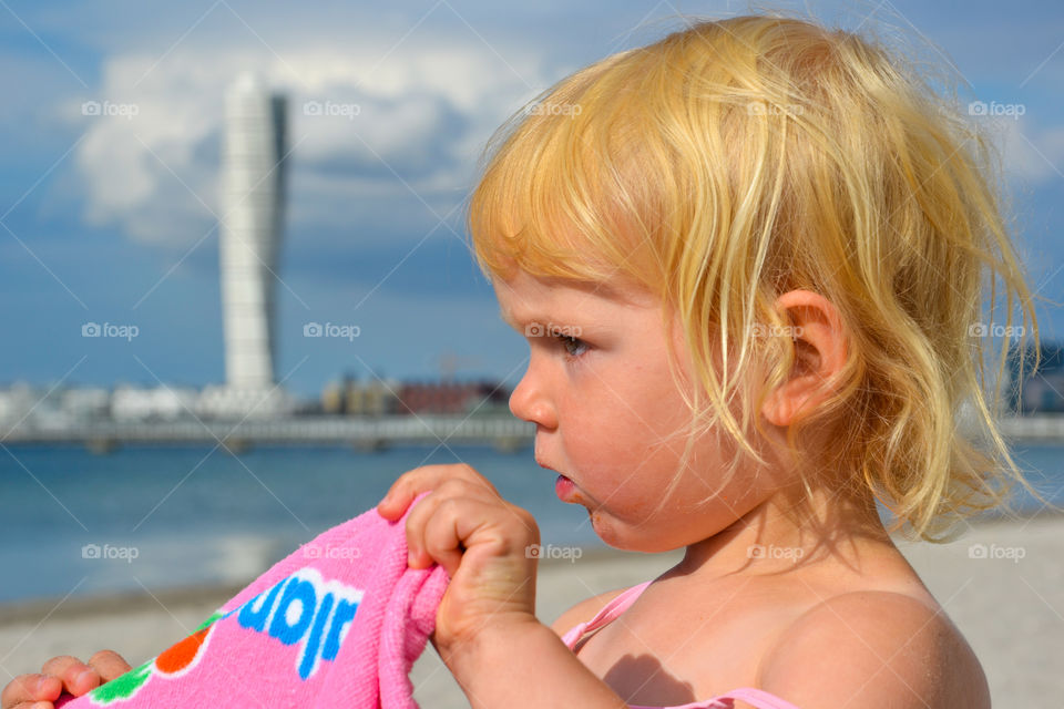 Young girl at Ribban beach in Malmö near The famous buildin Turning Torso in Sweden.